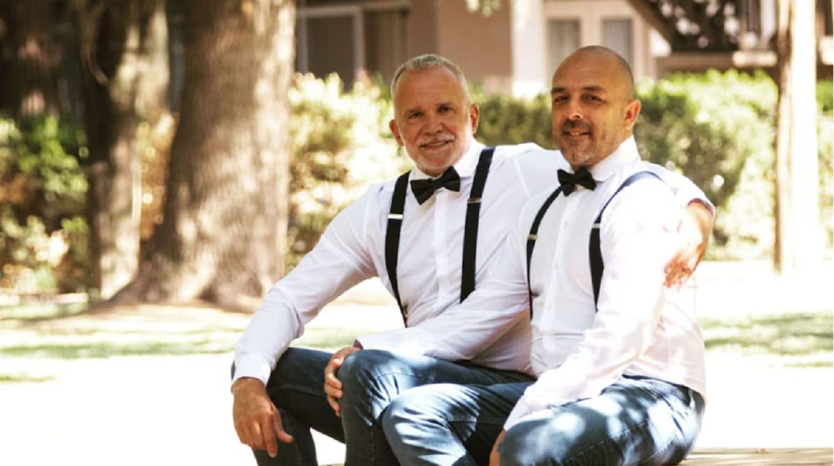 Pareja de adultos sonriendo a la cámara en una toma previa a su matrimonio legal.