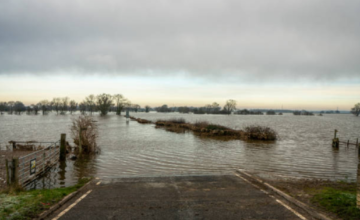 Camino rural de tierra anegado y destruido por lluvias intensas en el norte de Uruguay.