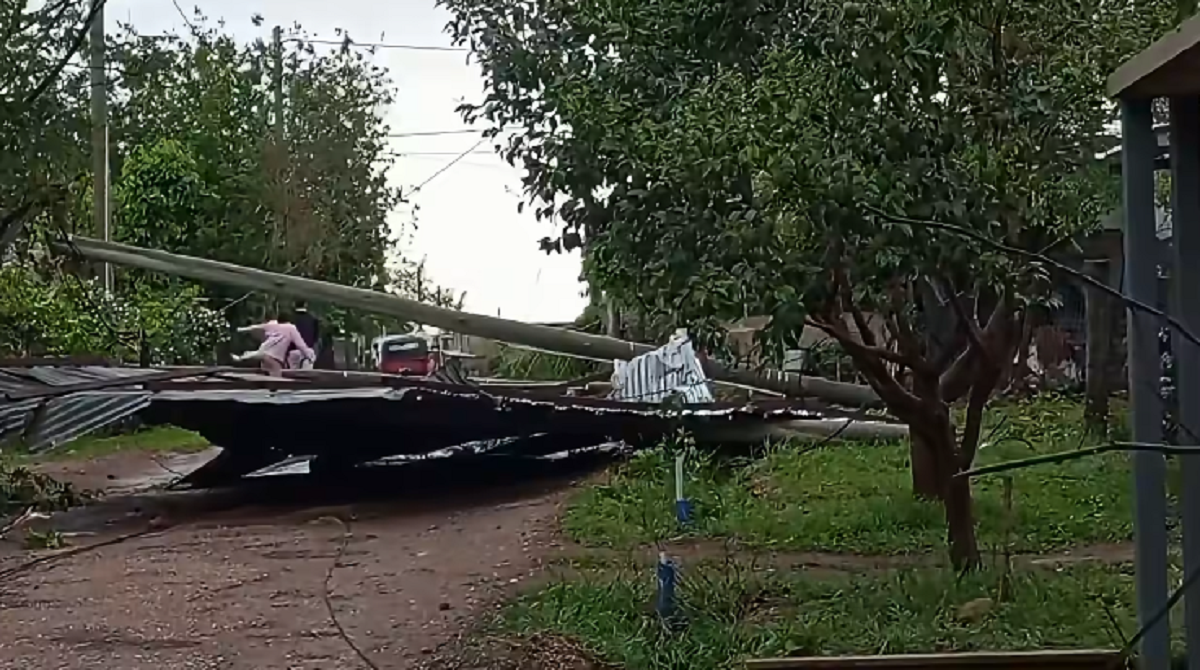 Techo de chapa de gran tamaño tirado en medio de una calle de tierra tras un fuerte temporal en Salto.